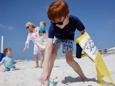 kid picking up litter on the beach in gulf shores