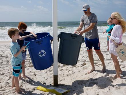 family cleaning up litter from the beach in gulf shores