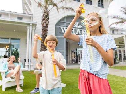 kids blowing bubbles on the lawn at Portside at The Wharf