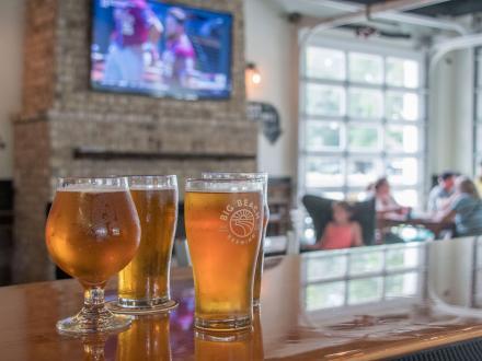 craft beer sitting on the bar with college football playing on a tv in the background at Big Beach Brewing, Gulf Shores local brewery