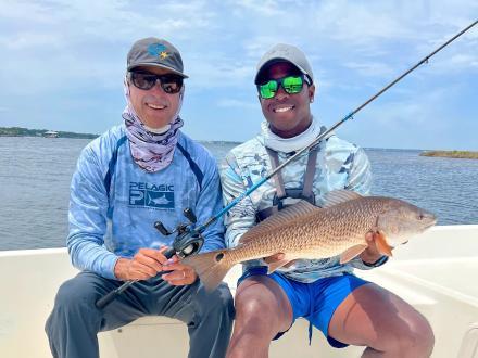 Anglers holding a redfish caught on an inshore fishing charter in Orange Beach