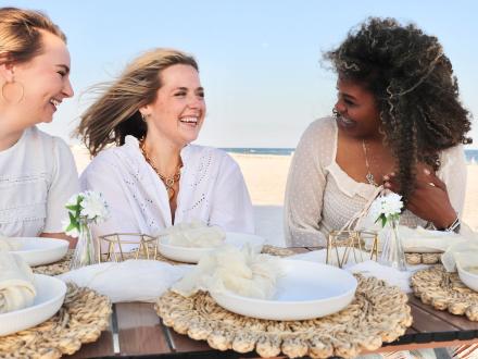 Friends enjoying a beachfront picnic by Beachside Blankets in Orange Beach