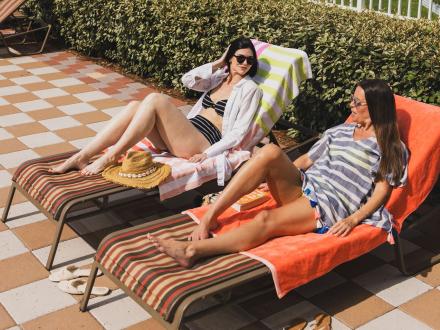 Women lounging on pool chairs at Phoenix Orange Beach beachfront condo