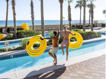 Couple jumping into lazy river at Phoenix West beachfront condo in Orange Beach
