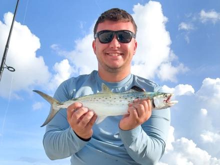 Angler holding a speckled trout caught while fishing on Alabama's Beaches