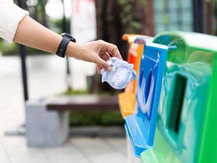 hand putting paper into a recycling bin
