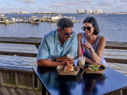 Couple dining on the waterfront deck at Avenue Pub restaurant in Orange Beach
