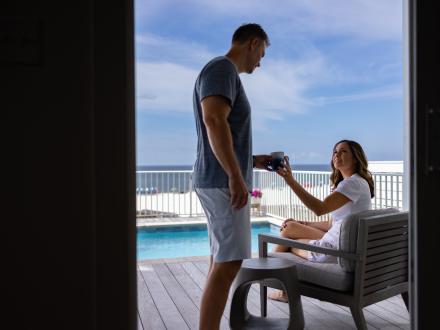 couple drinking coffee on the balcony of a beach house in orange beach
