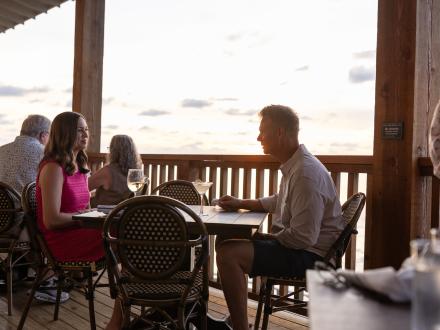 Couple dining on the outdoor deck at Jesse's on the Bay, fine dining waterfront restaurant in Gulf Shores