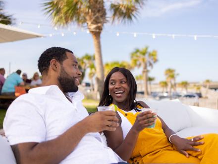 Couple sipping cocktails on the outdoor couches at The Gulf beachfront restaurant in Orange Beach