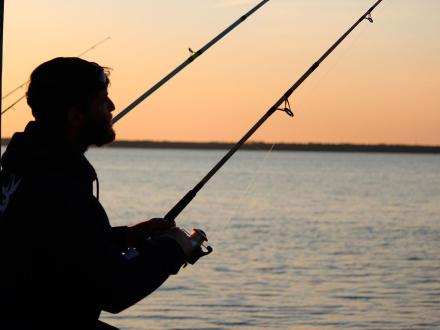 silhouette of an angler pier fishing at sunset in Gulf Shores