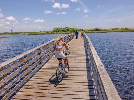 woman biking along the boardwalk trail over Lake Shelby in Gulf State Park