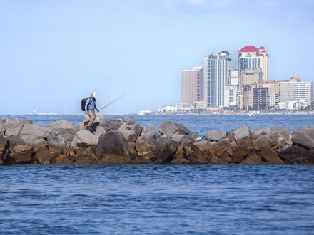 An angler nearshore fishing from the jetties at Alabama Point in Orange Beach