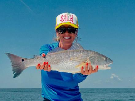 woman holding a large redfish caught while inshore fishing in gulf shores