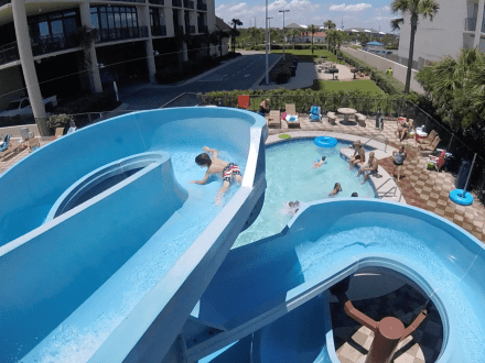 View of a young boy going down a waterslide from the top of the slide at Phoenix condo in Orange Beach