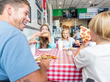 Family at a table enjoying pizza at Vinny's Pizzeria at the Wharf in Orange Beach