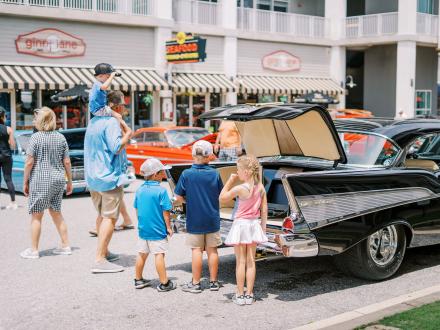 Family checking out a classic car at Bama Coast Cruisin' Car Show in Orange Beach