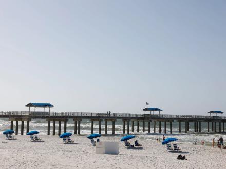 Beach chairs and umbrellas lined up along the shore at The Tides beachfront hotel in Orange Beach