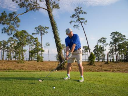 Man lining up a swing on the golf course at Peninsula Golf & Racquet Cub in Fort Morgan
