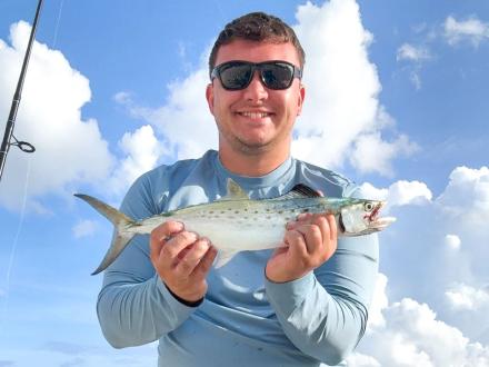 Man holding a speckled trout caught in the Gulf while fishing in Orange Beach