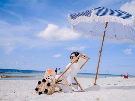 woman relaxing in a beach chair under an umbrella along the shoreline at the beach in gulf shores
