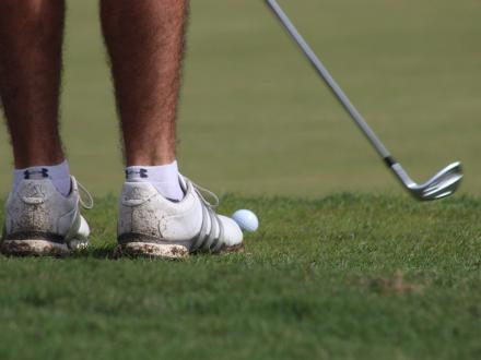 feet of a golfer about to swing on the course at Craft Farms Resort in Gulf Shores