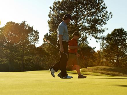 Dad and son walking along golf course at sunset in Gulf Shores