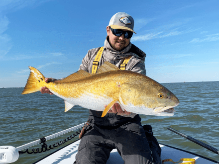 Angler holding redfish caught while inshore fishing in Orange Beach