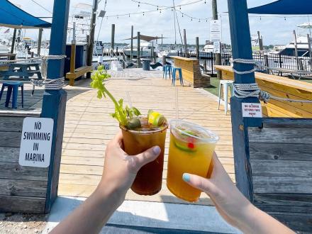 Hands cheersing cocktails at OSO waterfront restaurant and bar in Orange Beach