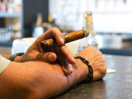hand holding a cigar at shore things cigars at the wharf in orange beach