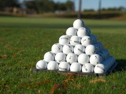 golf balls stacked in a pyramid sitting on the green
