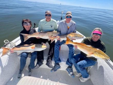 Anglers showing off redfish caught on an inshore fishing charter in Orange Beach