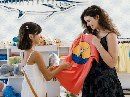 teens holding up a shirt at the wharf store in orange beach