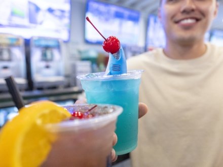 Couple cheersing coastal cocktails at The Hangout beachfront bar in Gulf Shores