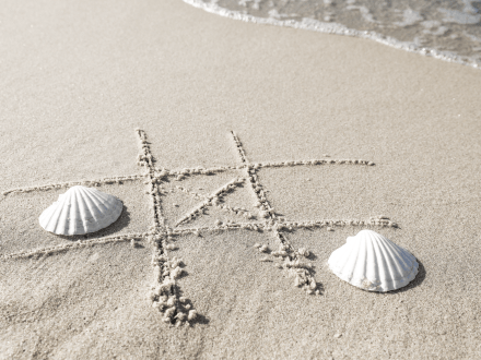 Tic-tac-toe drawn in the sand with seashells
