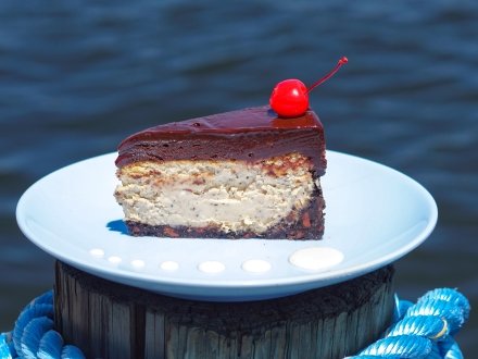 Bushwacker cheesecake topped with a rich chocolate glaze and cherry, served at OSO at Bear Point Harbor