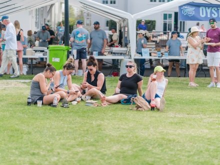 festival goers sitting on the grassy lawn at Fort Morgan Oyster Fest