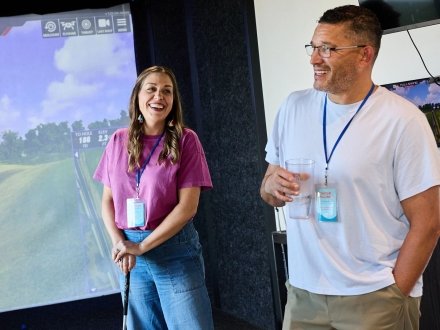 Couple laughing at a private swing suite golf simulator at Tee Off at The Wharf