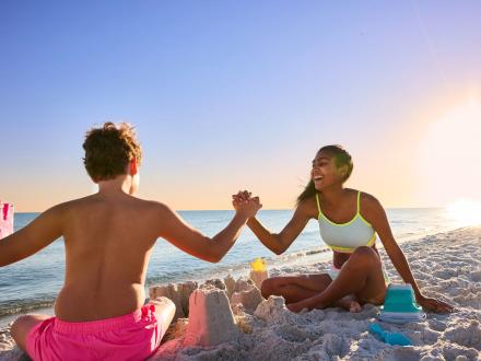 Teens high fiving while building sandcastles on the beach in Gulf Shores