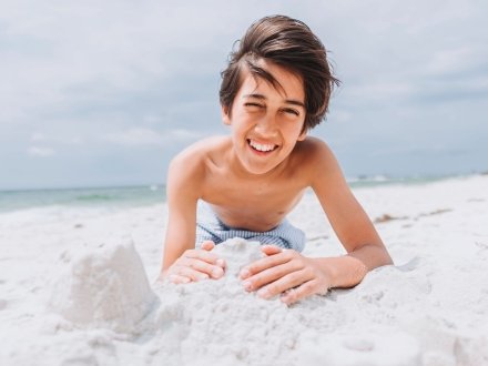 Boy building sandcastle on the shore at Alabama Point beach in Orange Beach