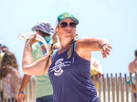 Woman throwing a fish across the stateline at Flora-Bama's Annual Mullet Toss event in Orange Beach