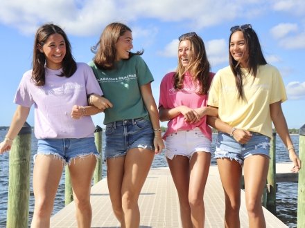 Girls wearing Shoreline Supply t-shirts and walking along a boardwalk in Orange Beach 