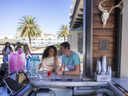 Couple sitting at the bar with shopping bags at the courtyard in SanRoc Cay