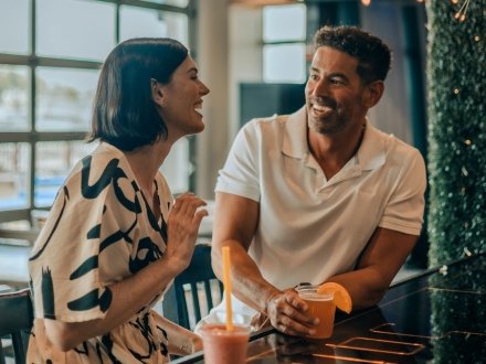 Couple with cocktails at a bar at The Wharf in Orange Beach