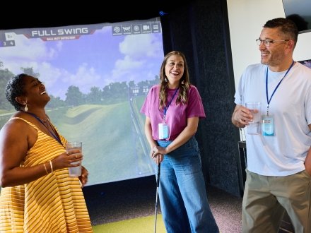 Friends playing virtual golf at Tee Off TopGolf SwingSuites at The Wharf