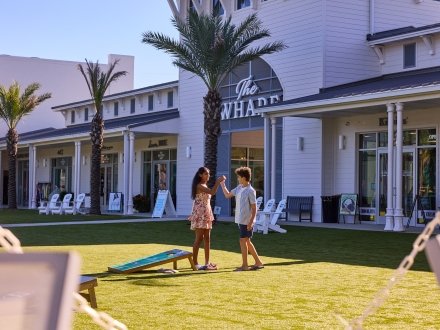Family playing in the grassy lawn area at Portside at The Wharf in Orange Beach