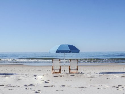 Beach chairs sitting under an umbrella on the beach in Gulf Shores