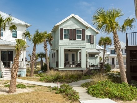 Charming beach house rental in Orange Beach, Alabama, surrounded by palm trees and coastal landscaping