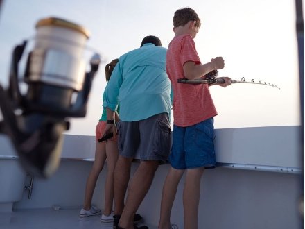 Family with kids fishing on an Orange Beach fishing charter.