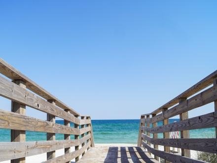 Wooden Gulf Access Boardwalk in Gulf Shores, Alabama, with clear blue skies and turquoise waters